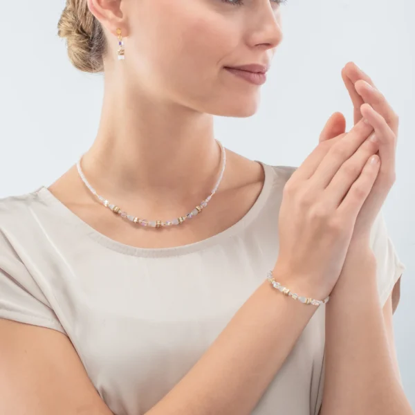 Modell trägt das Armband Mini Cubes gold weiß von COEUR DE LION – stilvoll kombiniert für einen eleganten Look.